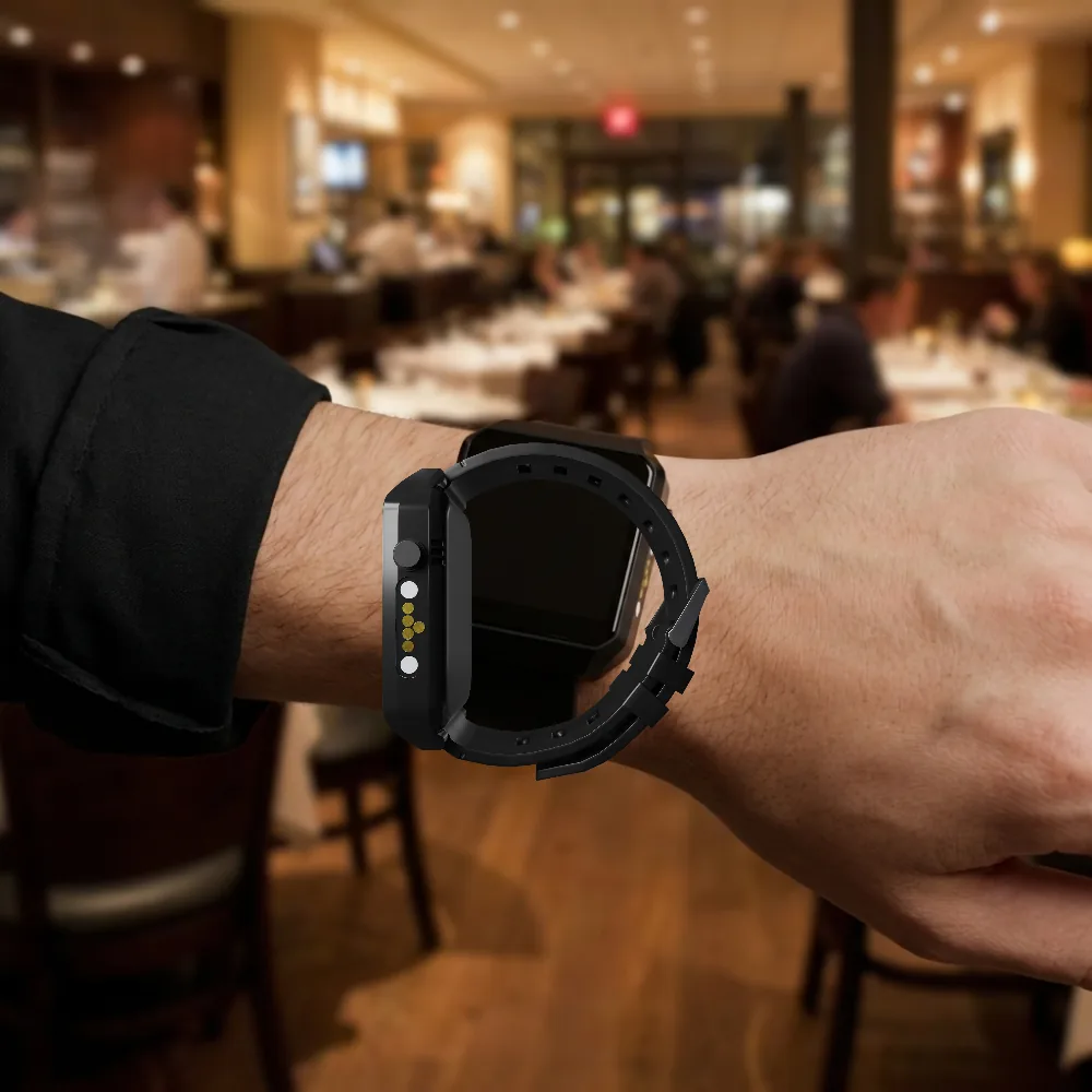A Vycall A35WP mobile call pager on a waiter's wrist in a restaurant